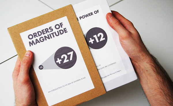 Two hands holding an Orders of Magnitude booklet