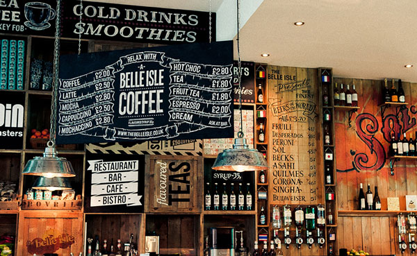 A wall behind the bar with various graphically designed signage and menus